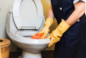 cleaning toilet with wearing yellow gloves