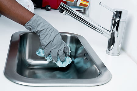 Cleaning a stainless steel sink with gloves on