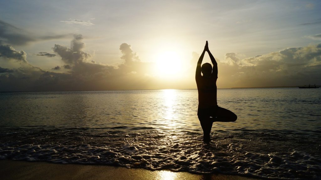 A man doing yoga in the morning while standing in sea water