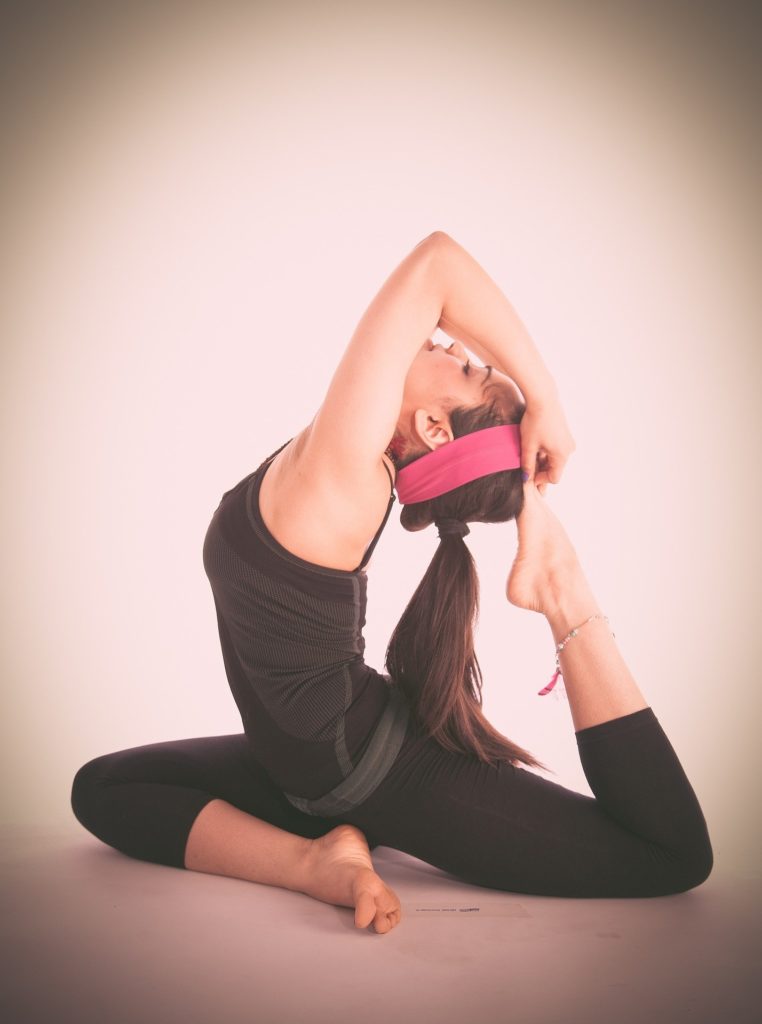 A young girl in black dress performing a variation of pigeon pose