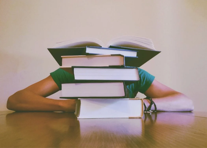 Tired person with Ph.D. books on table