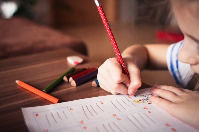 A kid writing with pencil